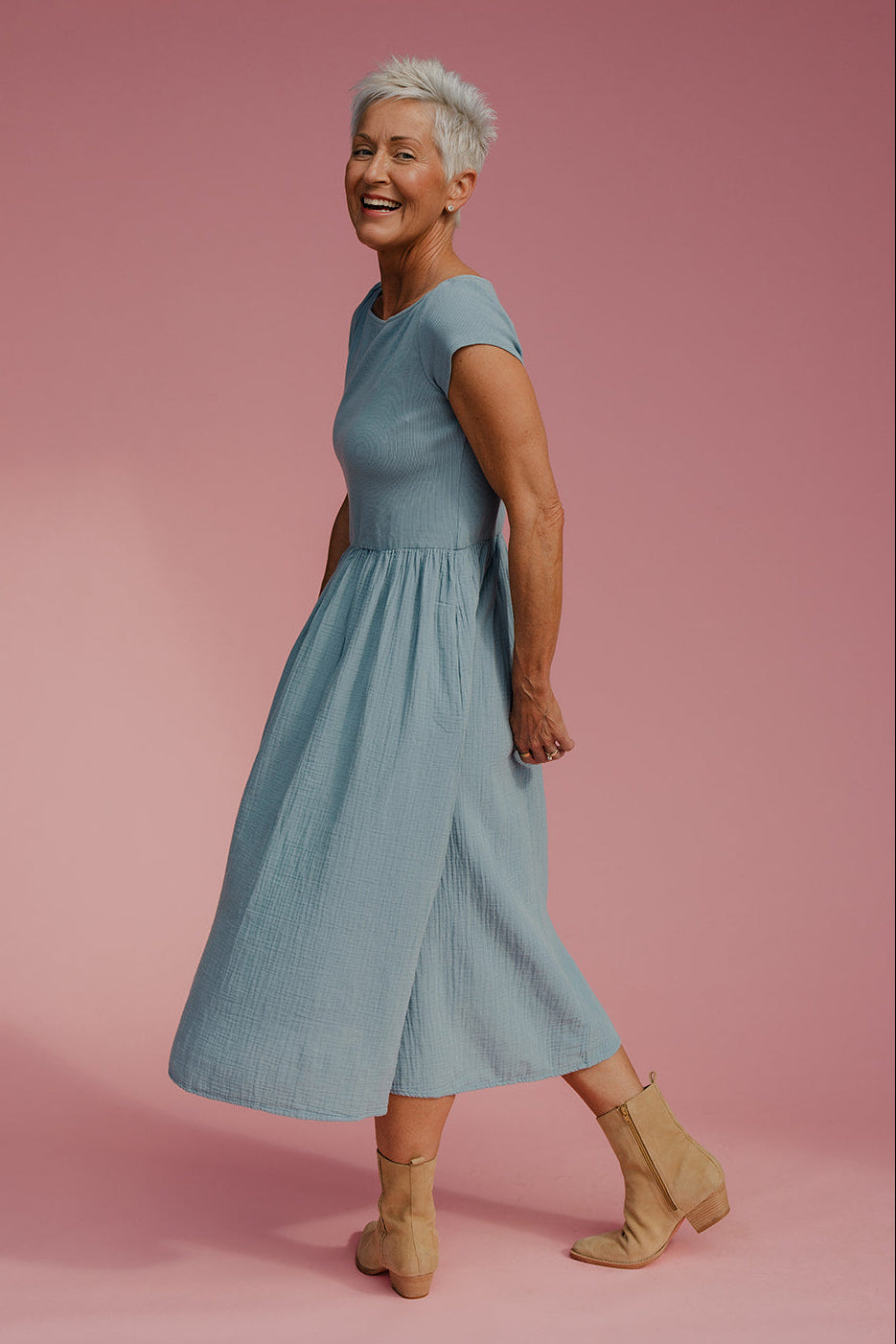 Woman in a light blue dress standing against a pink background