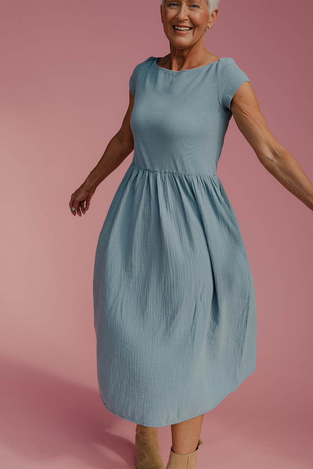 Woman wearing a light blue dress against a pink background