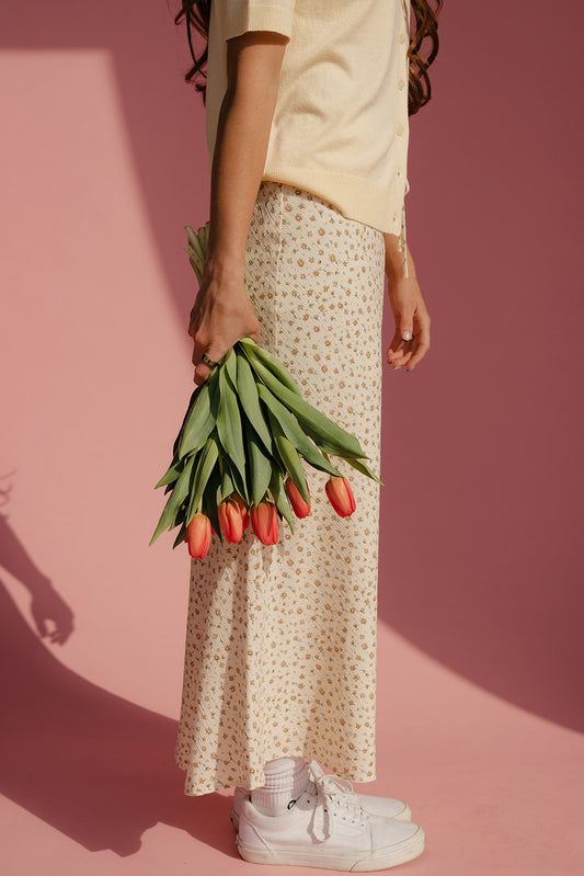 Person holding tulips against a pink background