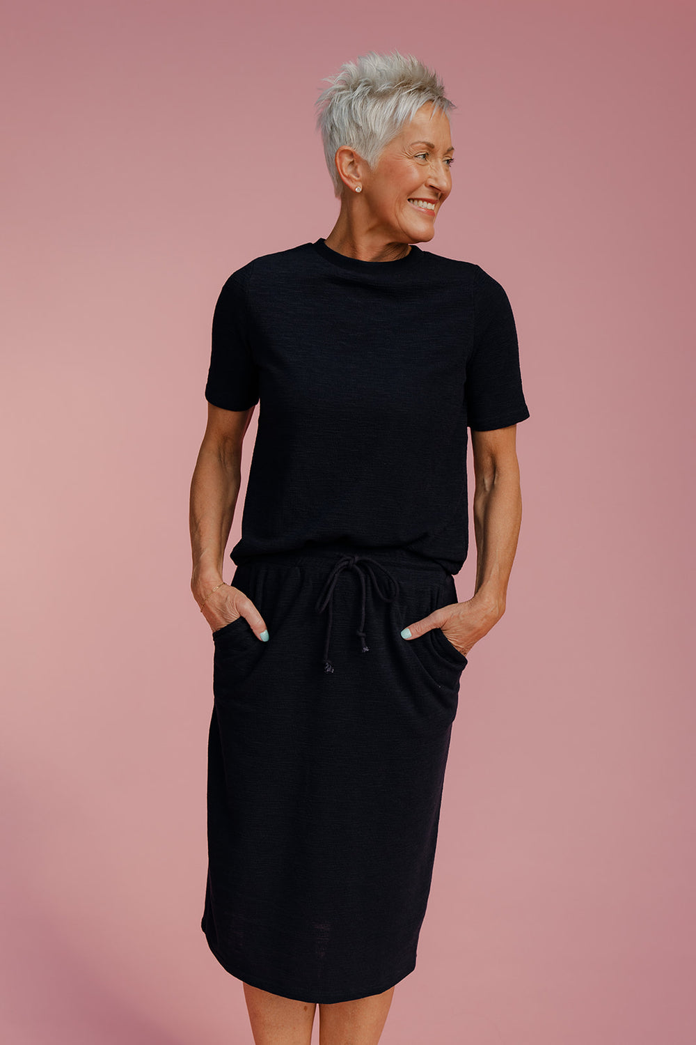 Woman wearing a black dress against a pink background