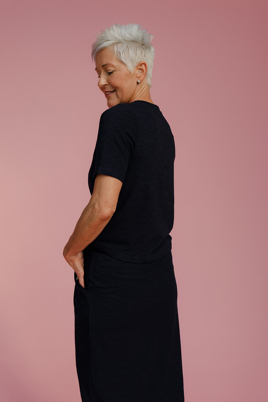 Woman wearing a black outfit against a pink background