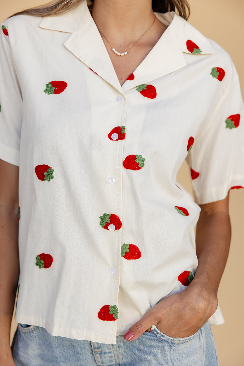 a person wearing a white shirt with red and green strawberries on it