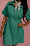 Green dress worn by a person with a pink background