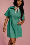 Woman wearing a green dress with a pink background