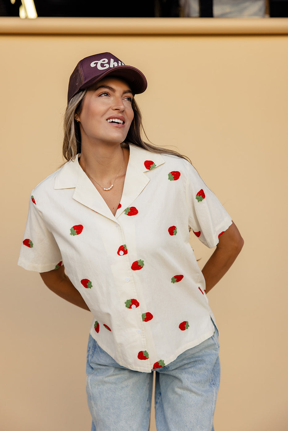 a woman wearing a hat and a white shirt with strawberries on it