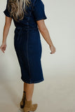 Person wearing a dark blue denim dress with a plain background