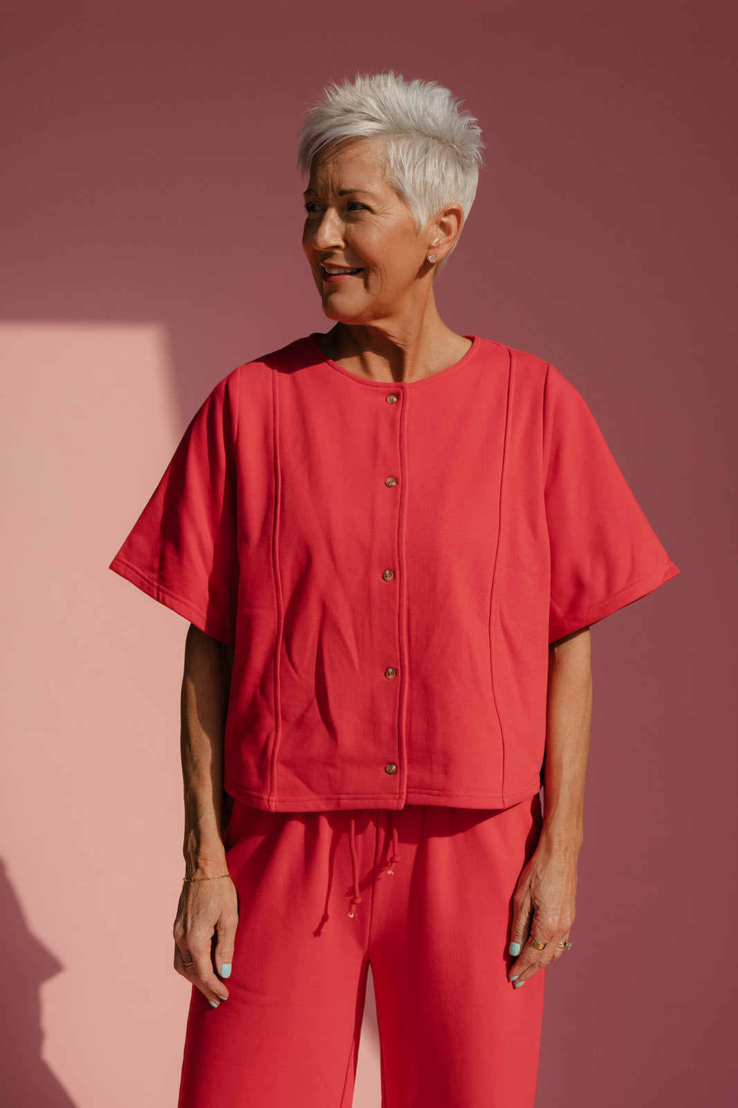 Woman wearing a red outfit against a pink background