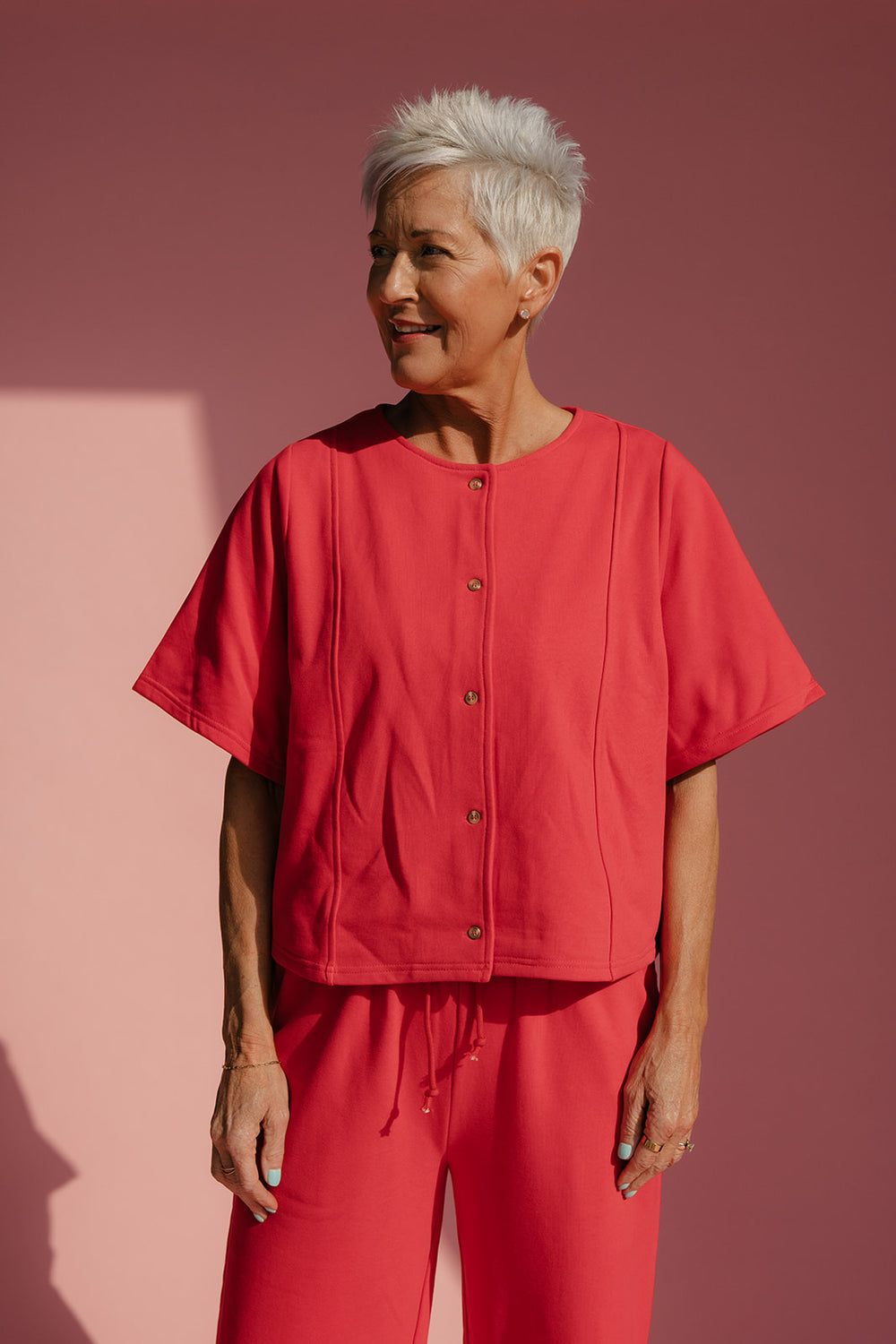 Woman wearing a red outfit against a pink background