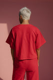 Person wearing a red outfit standing against a pink wall