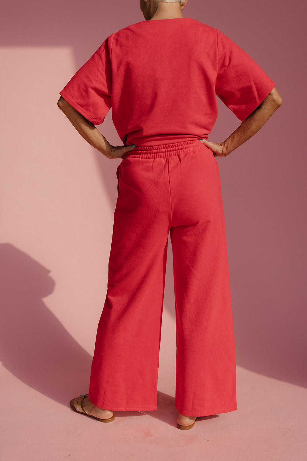 Person wearing a red outfit against a pink background