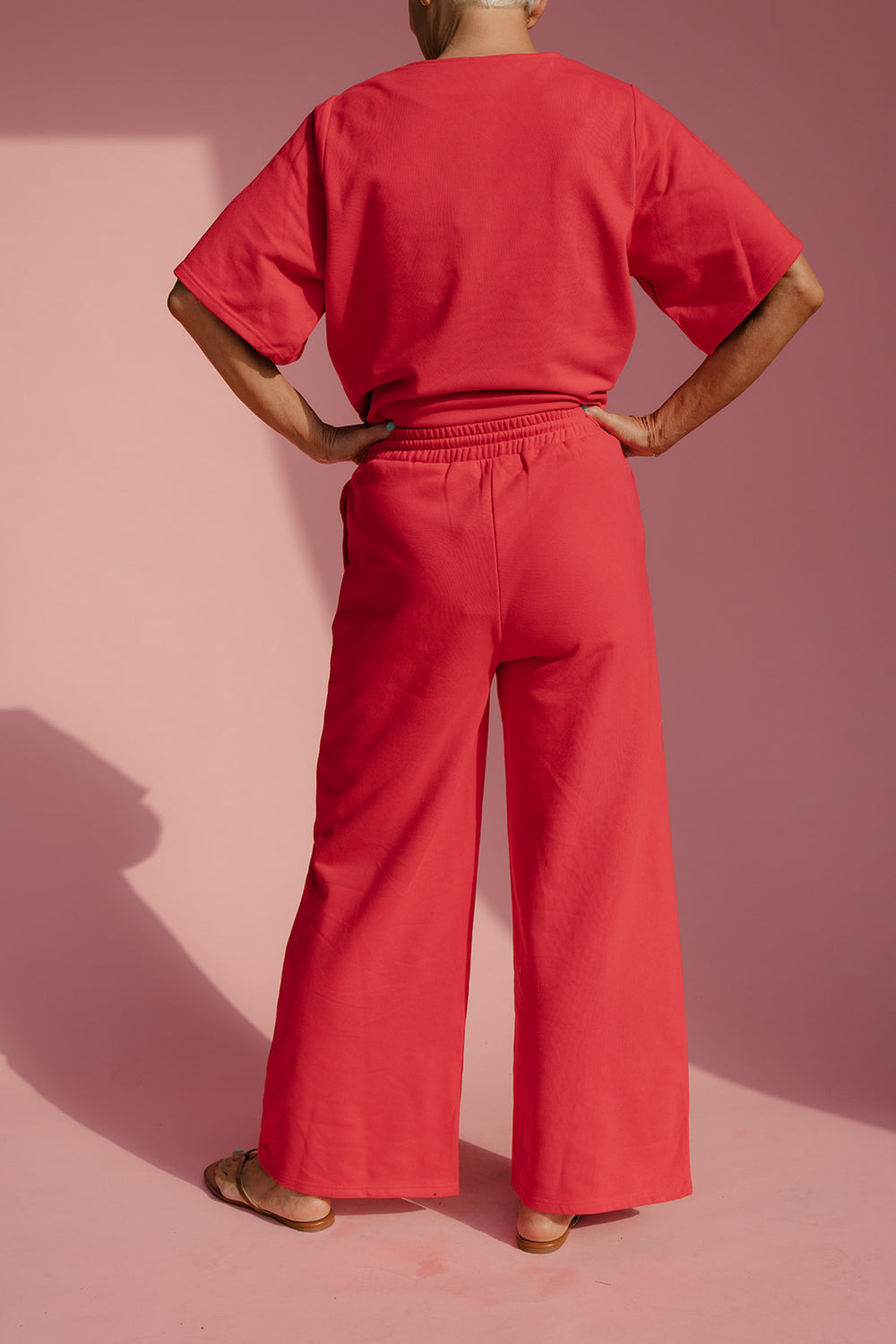 Person wearing a red outfit against a pink background