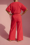 Person wearing a red outfit against a pink background
