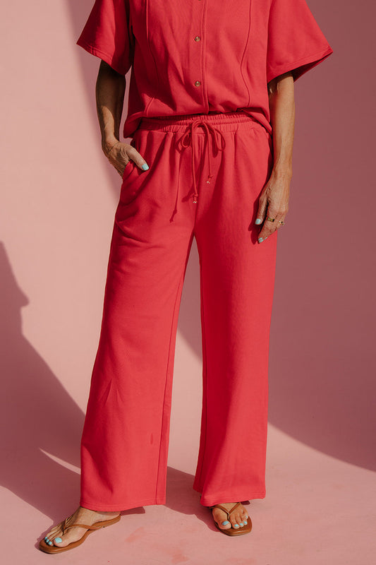 Person wearing a red outfit against a pink background