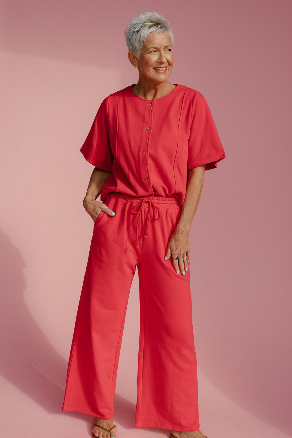 Woman wearing a red outfit against a pink background