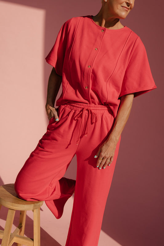 Person wearing a red outfit against a pink background