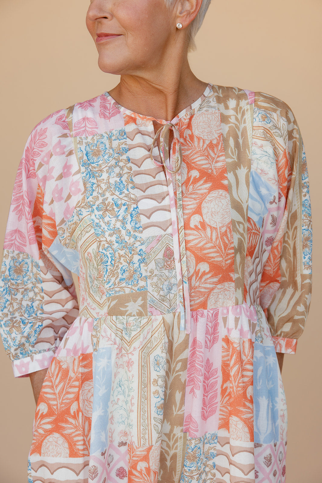 Woman wearing a colorful patterned dress against a beige background