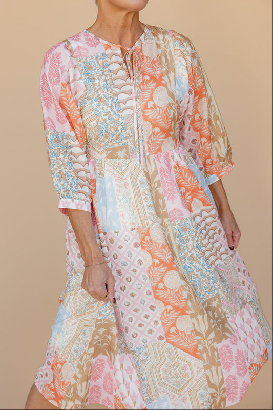 Woman wearing a colorful patterned dress against a beige background