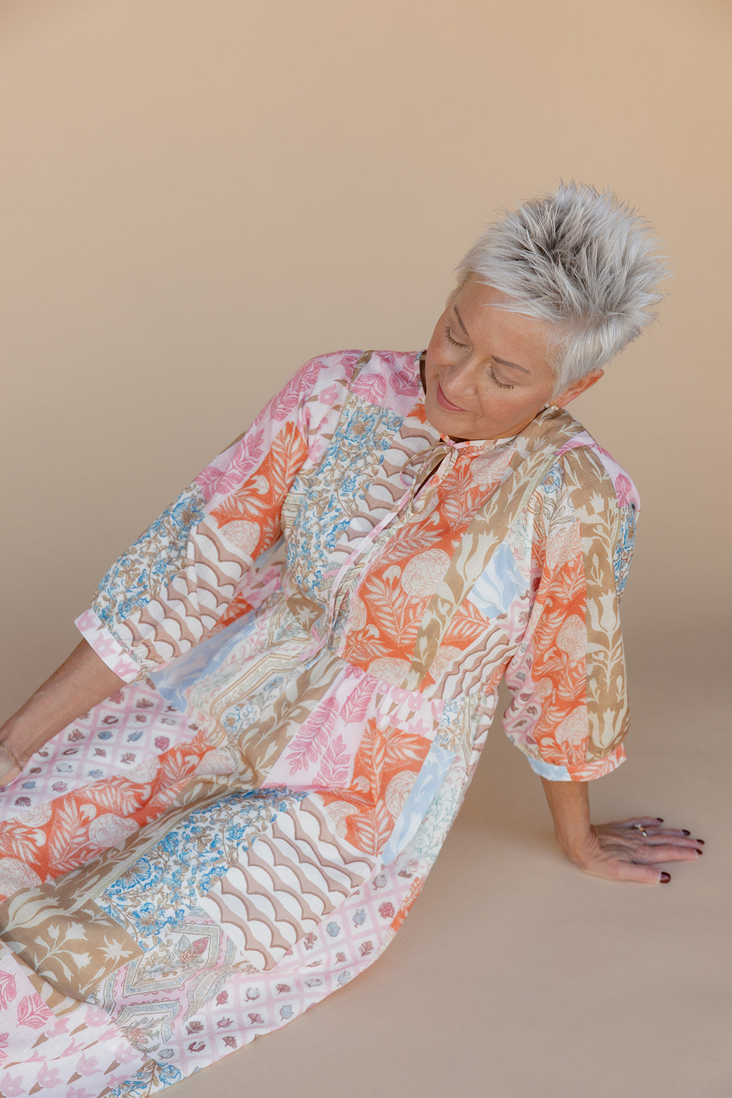 Woman wearing a colorful floral dress on a beige background