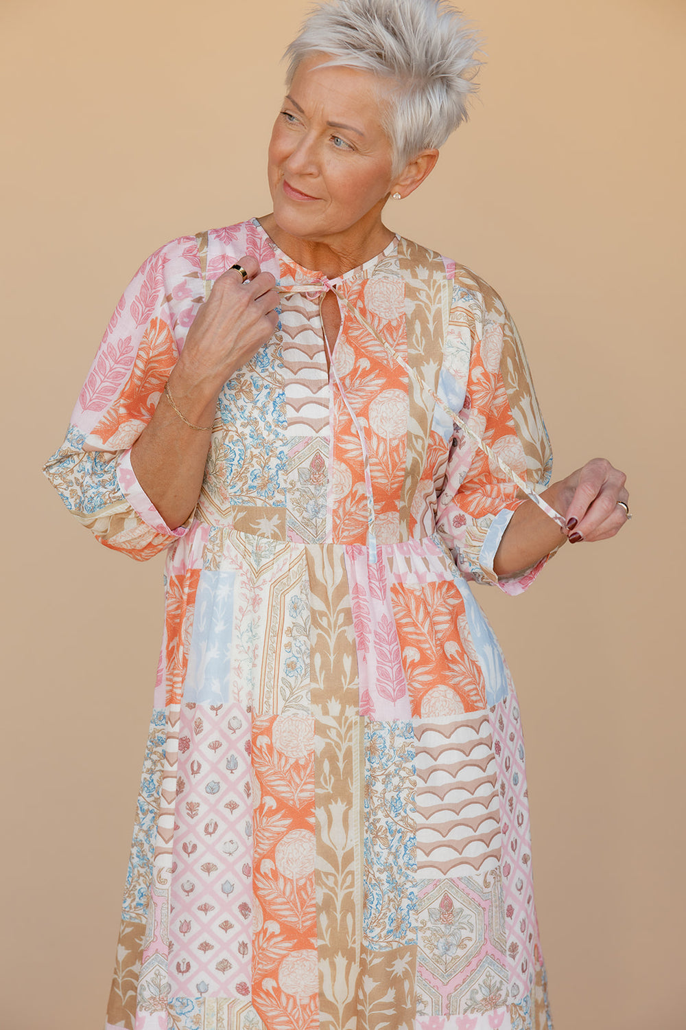 Woman wearing a patterned dress against a beige background