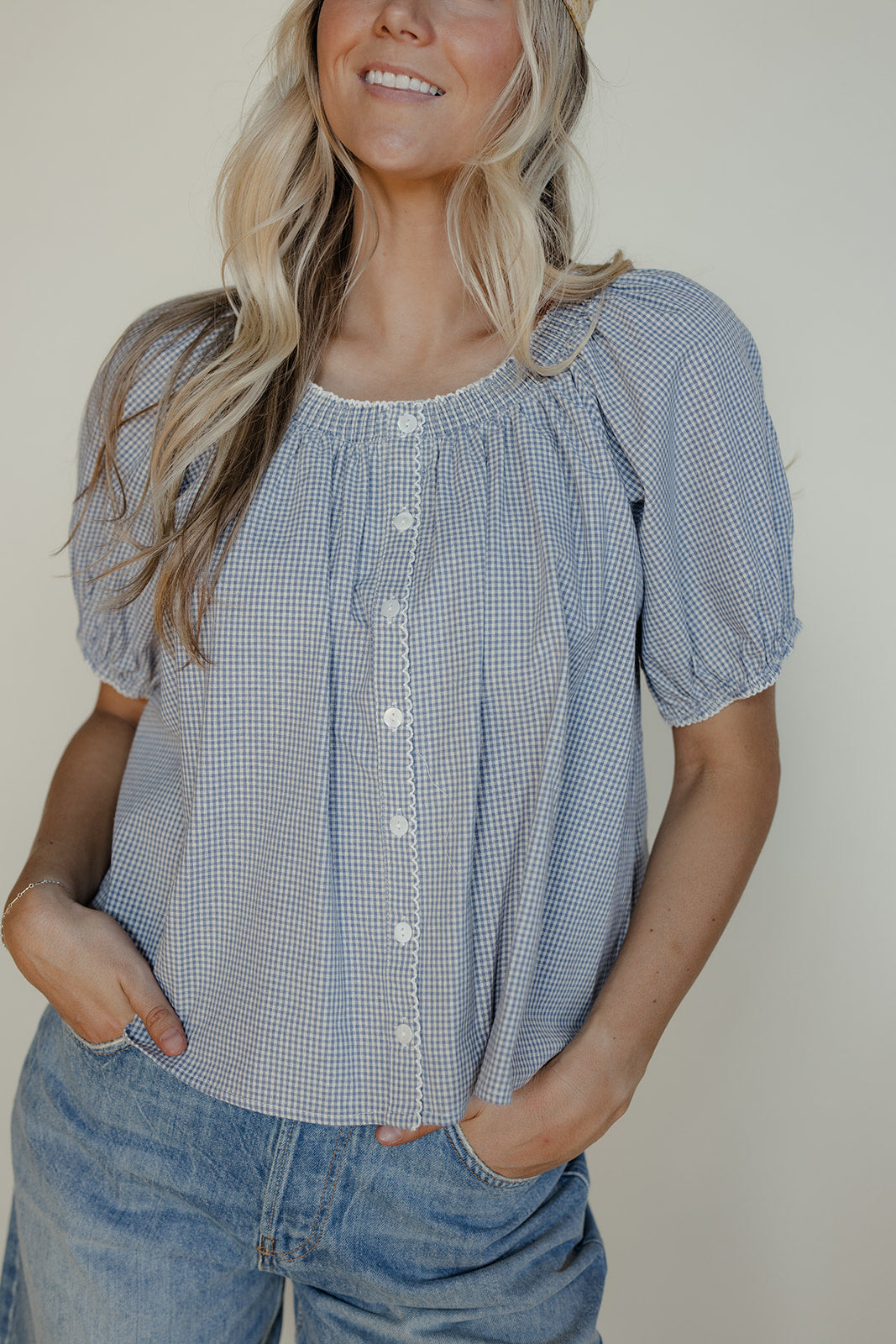 Woman wearing a blue checkered blouse with short sleeves against a plain background