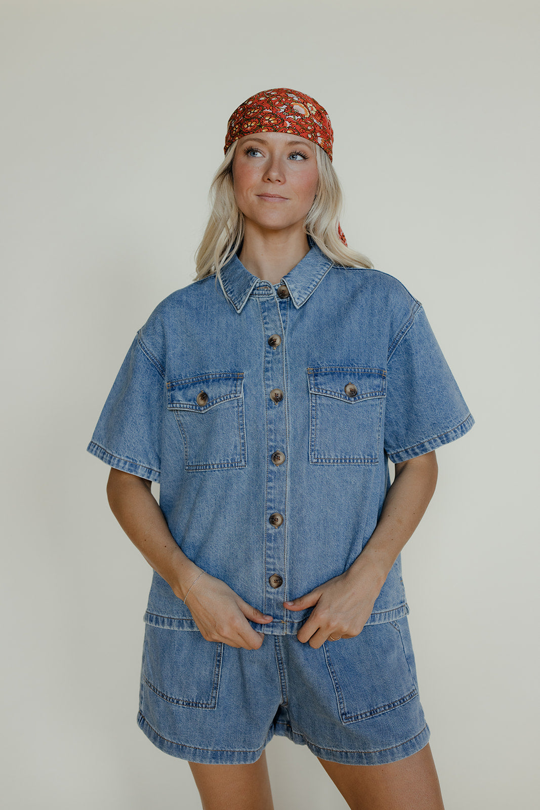 Person wearing a denim outfit with a red bandana on a plain background