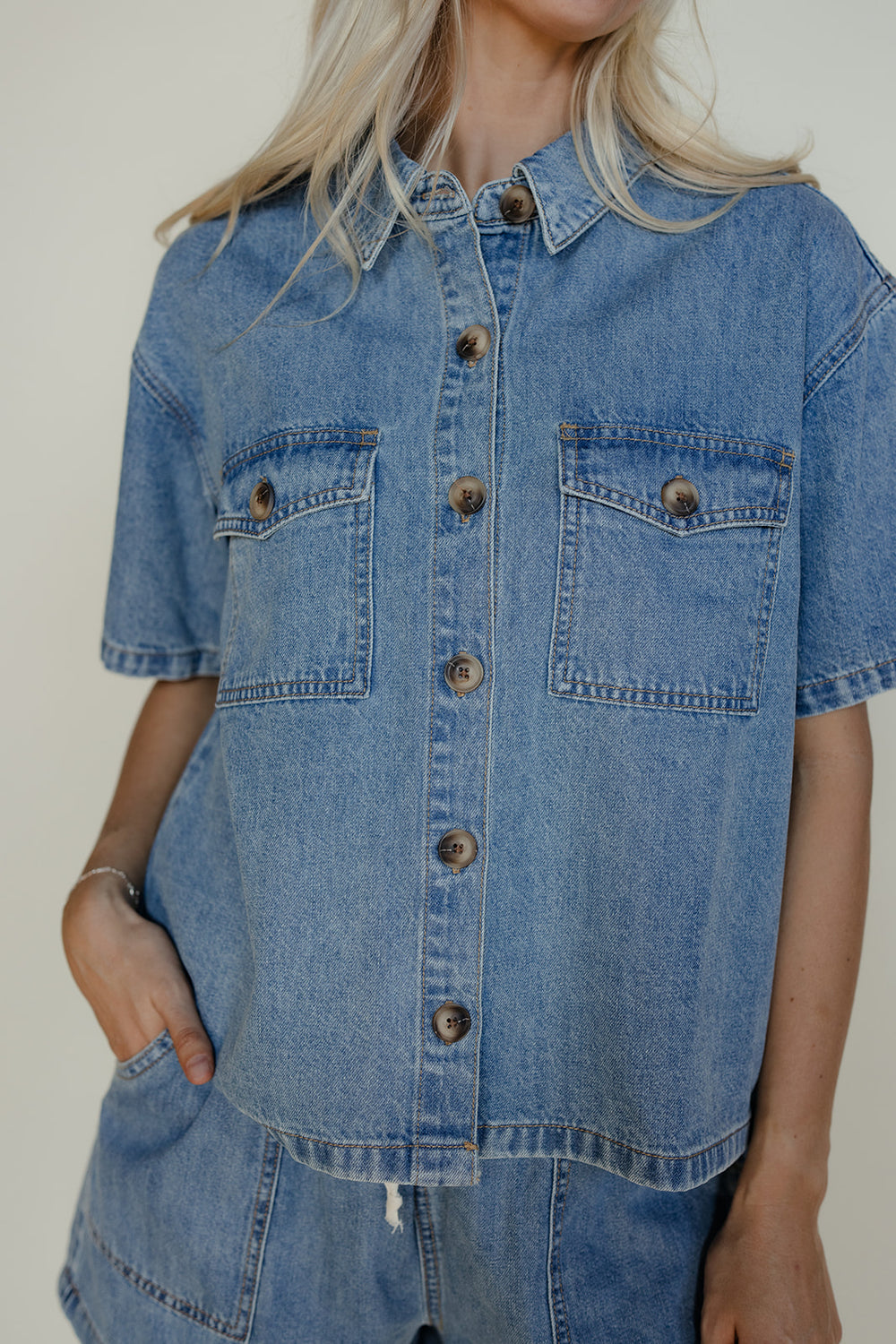 Person wearing a denim shirt with a neutral background