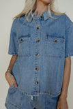 Person wearing a denim shirt with a neutral background