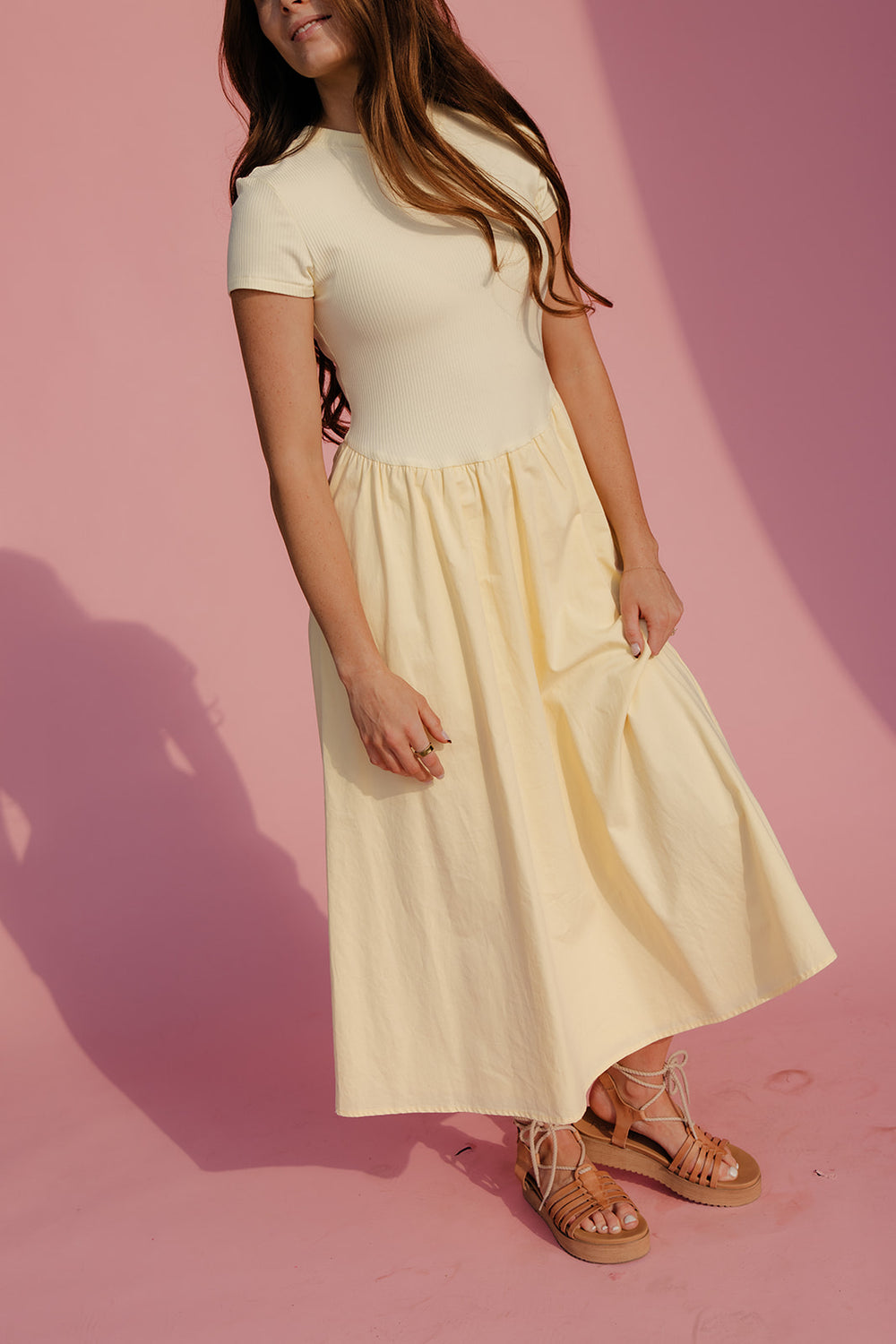 Woman wearing a light-colored dress against a pink background