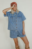 Woman wearing a denim outfit with a headscarf against a plain background