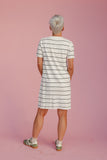 Person wearing a striped dress standing against a pink background