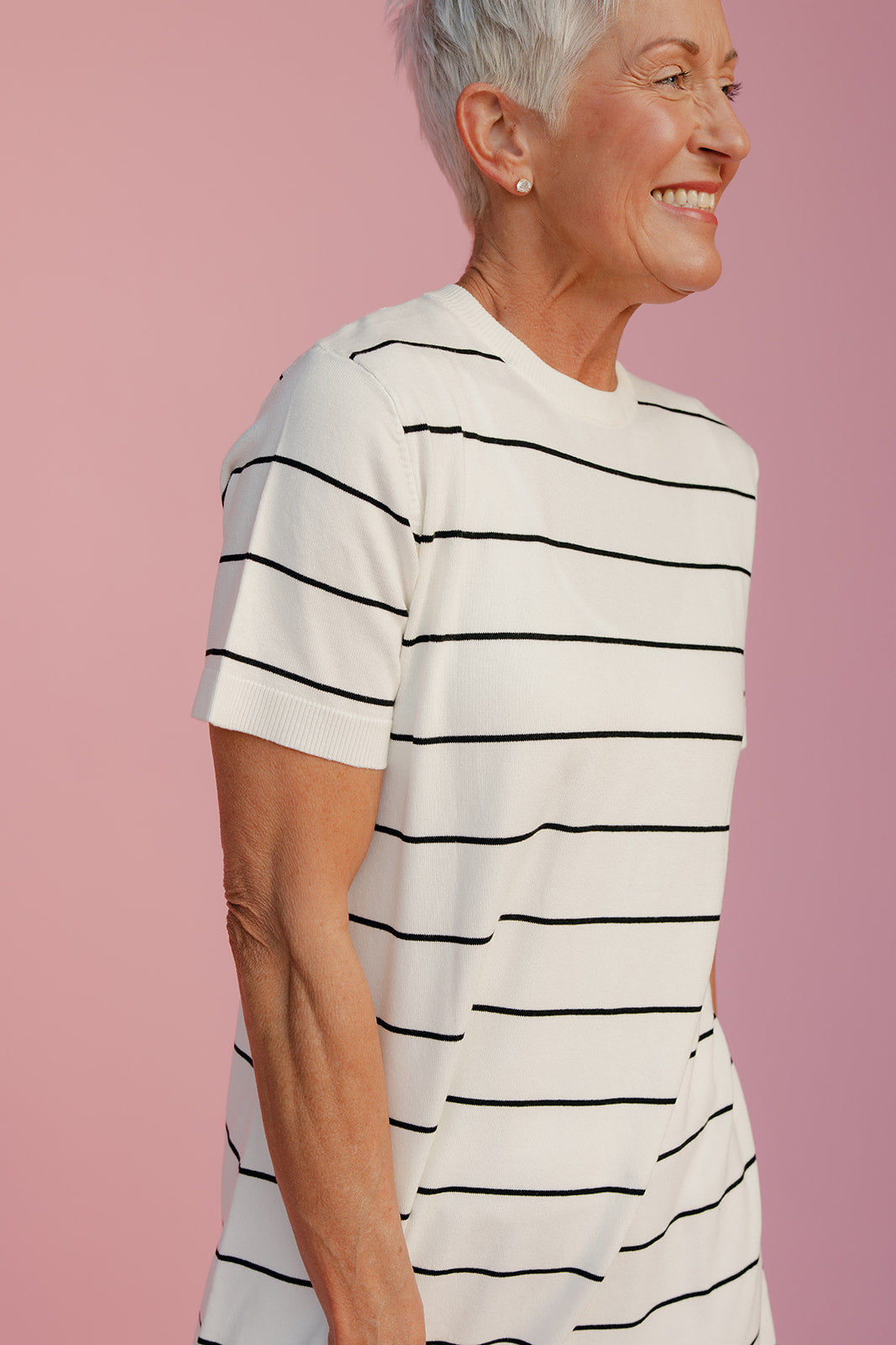 Woman wearing a white t-shirt with black stripes against a pink background