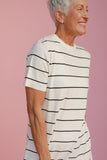 Woman wearing a white t-shirt with black stripes against a pink background