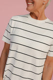 Person wearing a white t-shirt with black horizontal stripes against a pink background