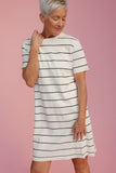 Woman wearing a black and white striped dress against a pink background