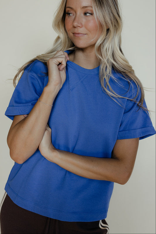 Woman wearing a blue t-shirt against a plain background