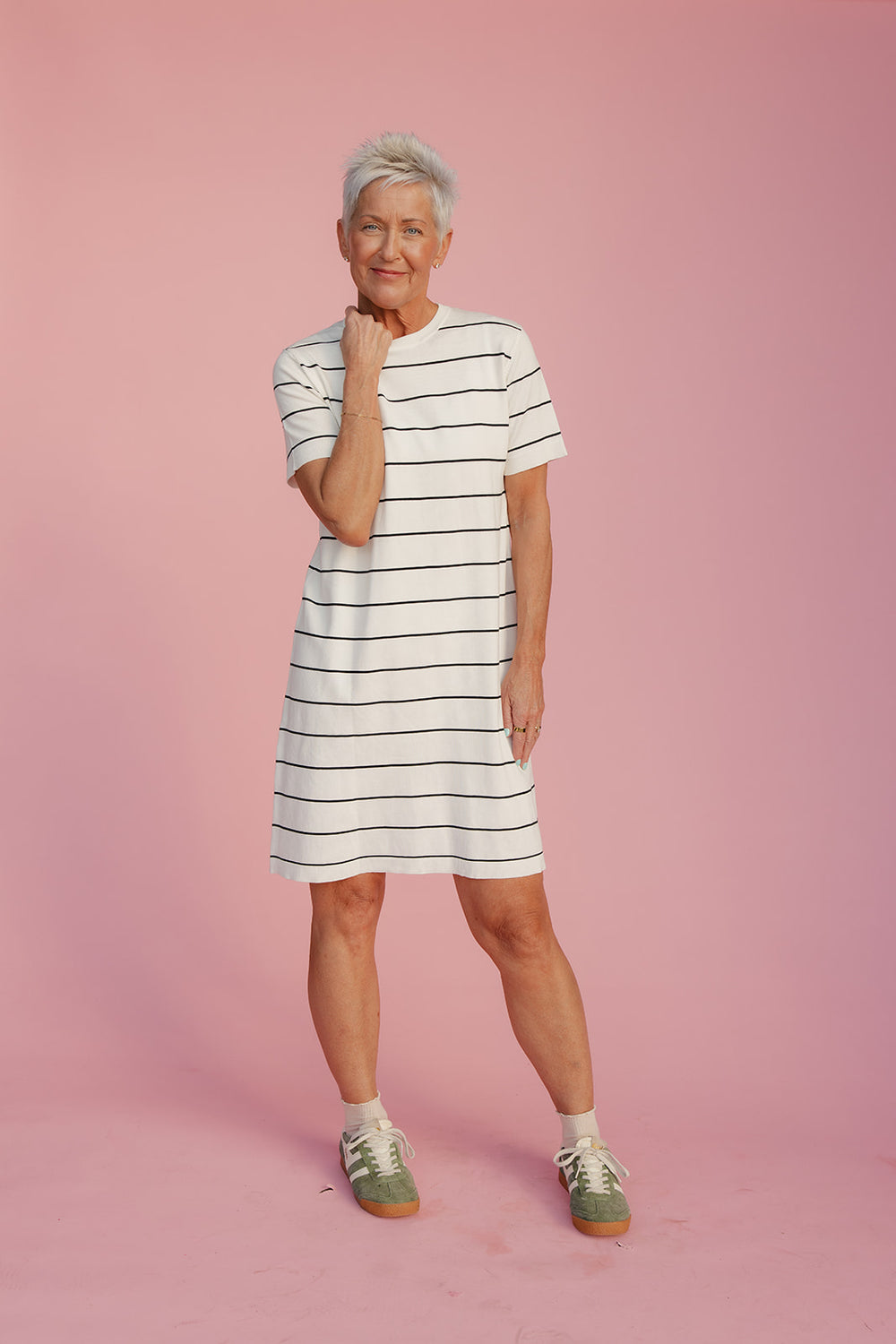 Woman wearing a striped dress against a pink background