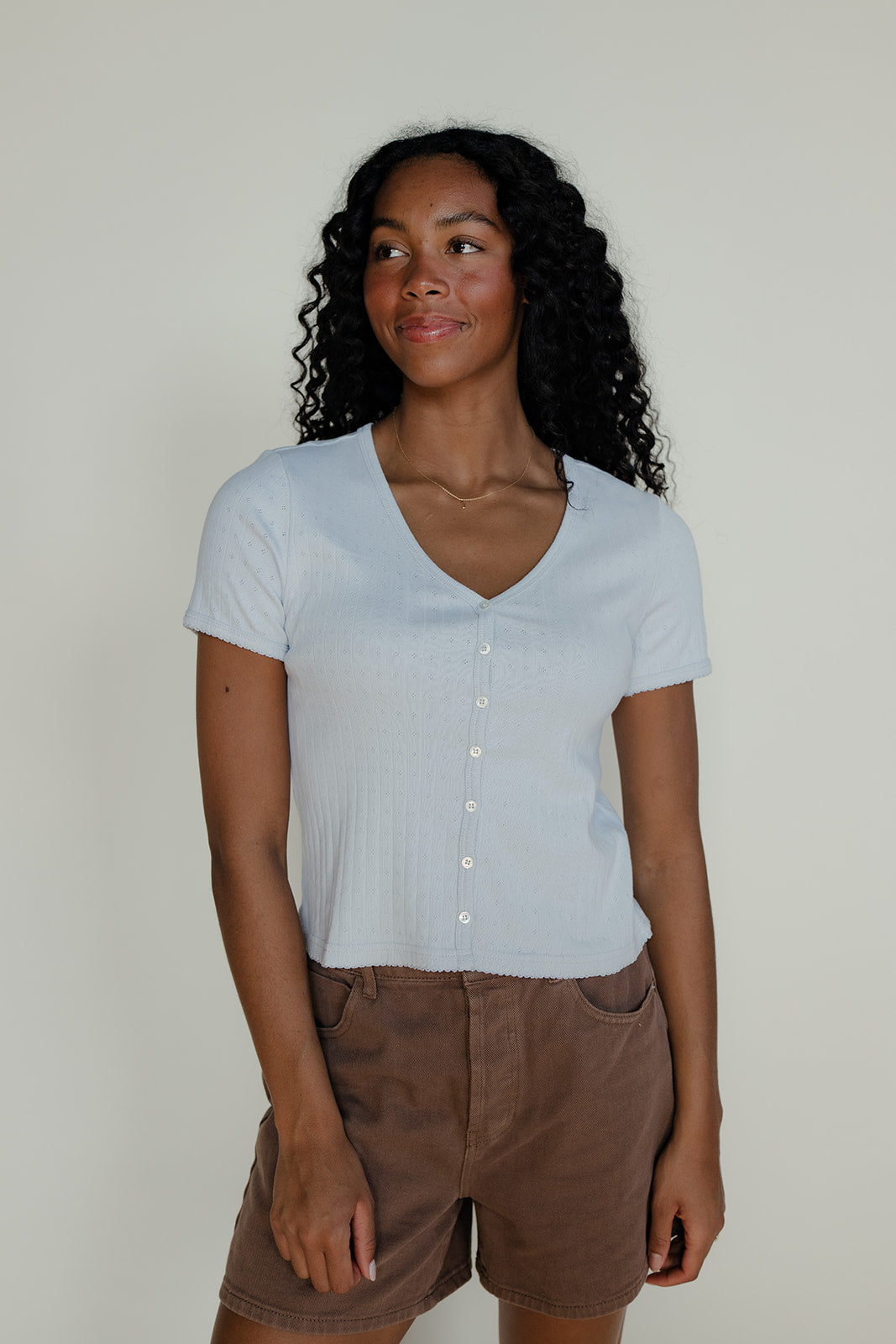 Woman wearing a light blue v-neck button up tee