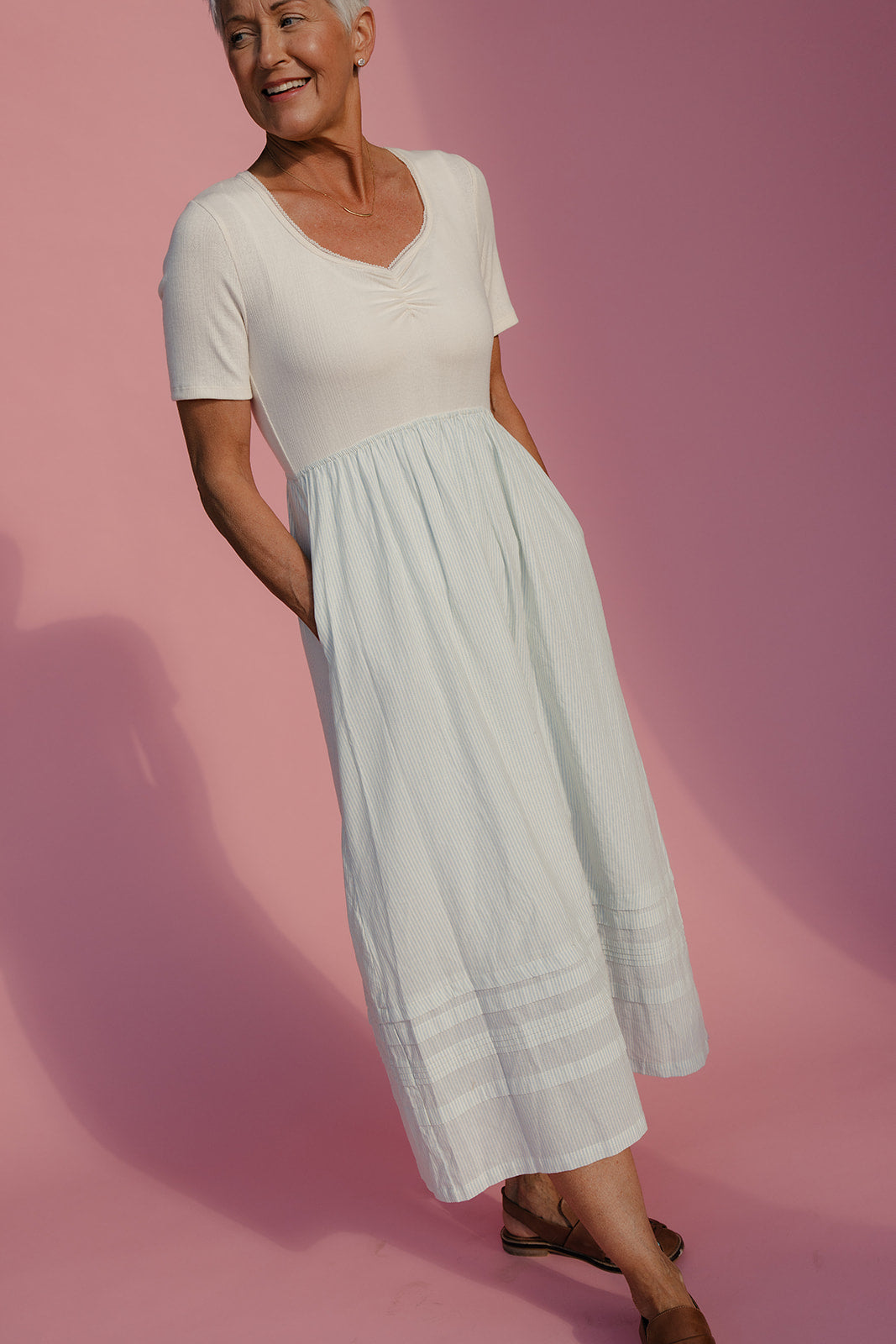 Woman wearing a white dress against a pink background