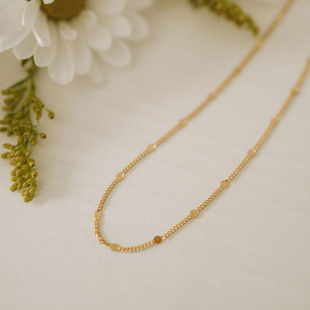a gold necklace on a white surface