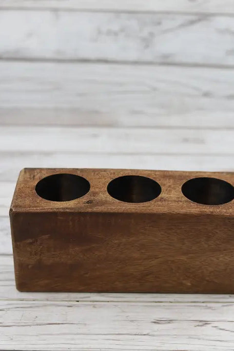 Wooden block with three cylindrical holes on a wooden surface