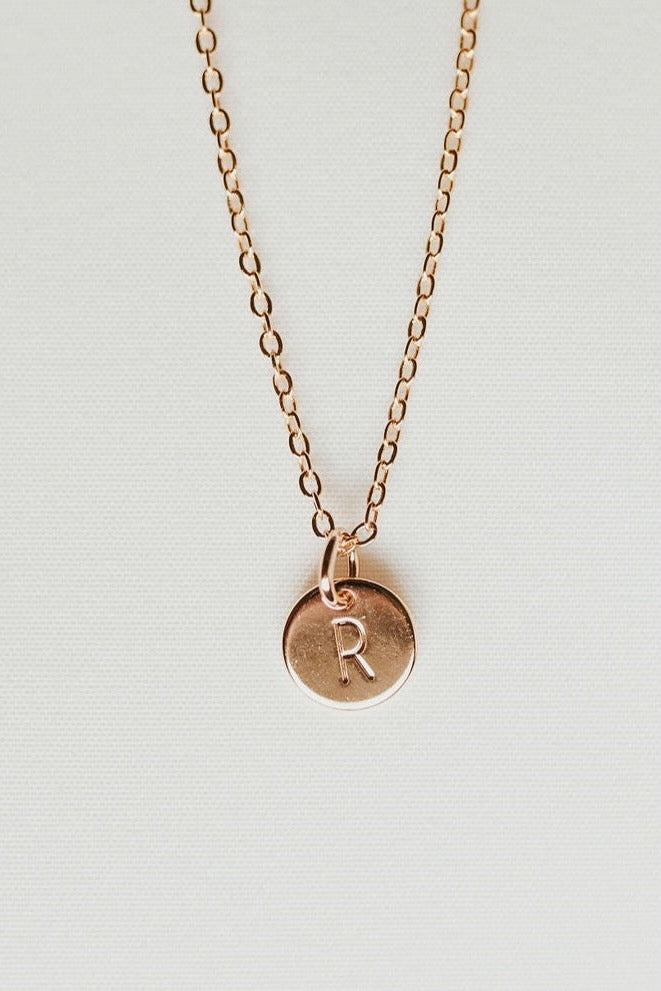 a gold necklace with a letter on it