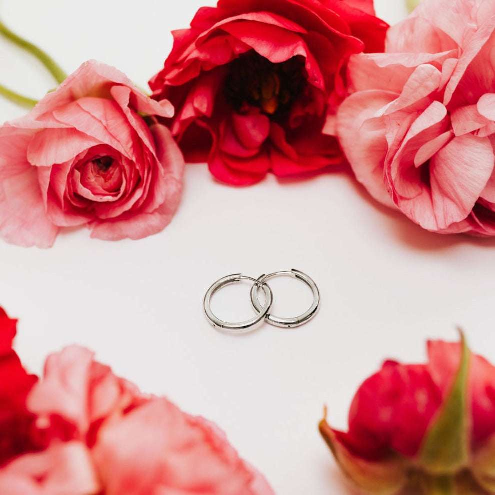 a pair of earrings next to pink flowers