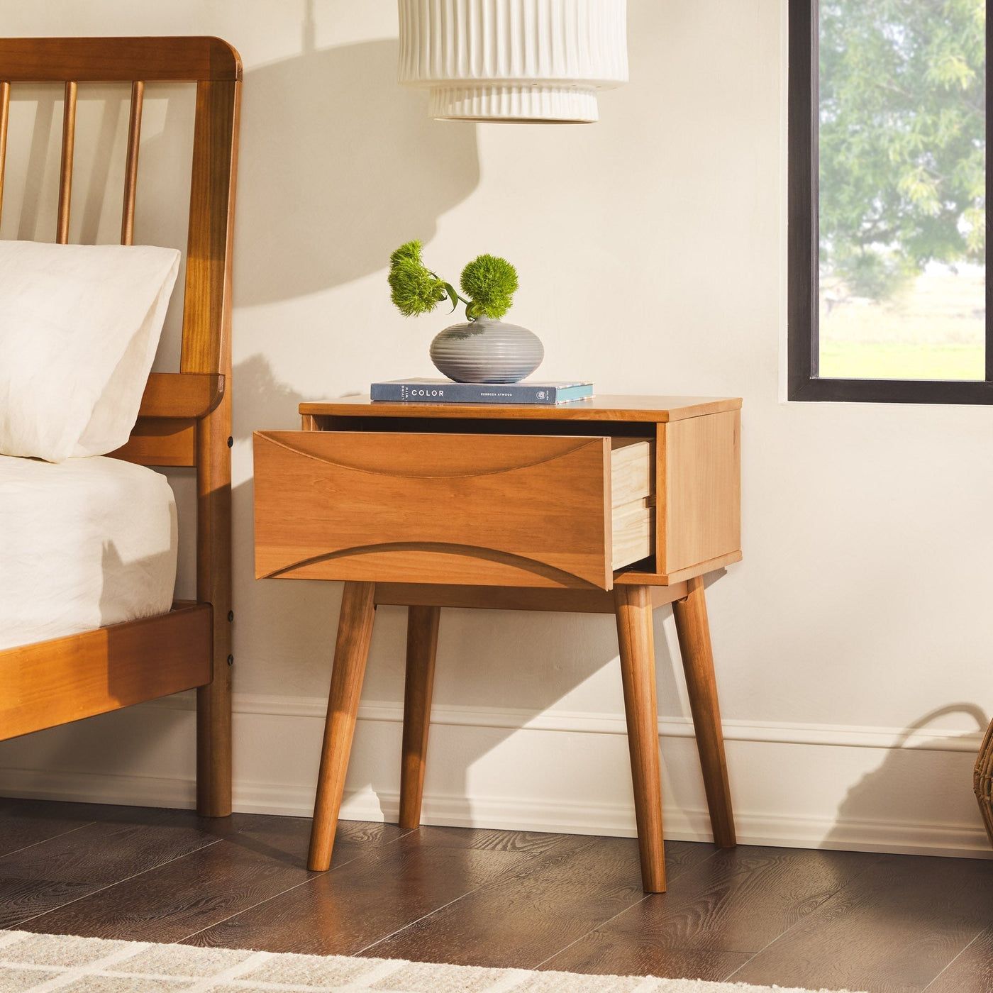 a wooden nightstand next to a bed