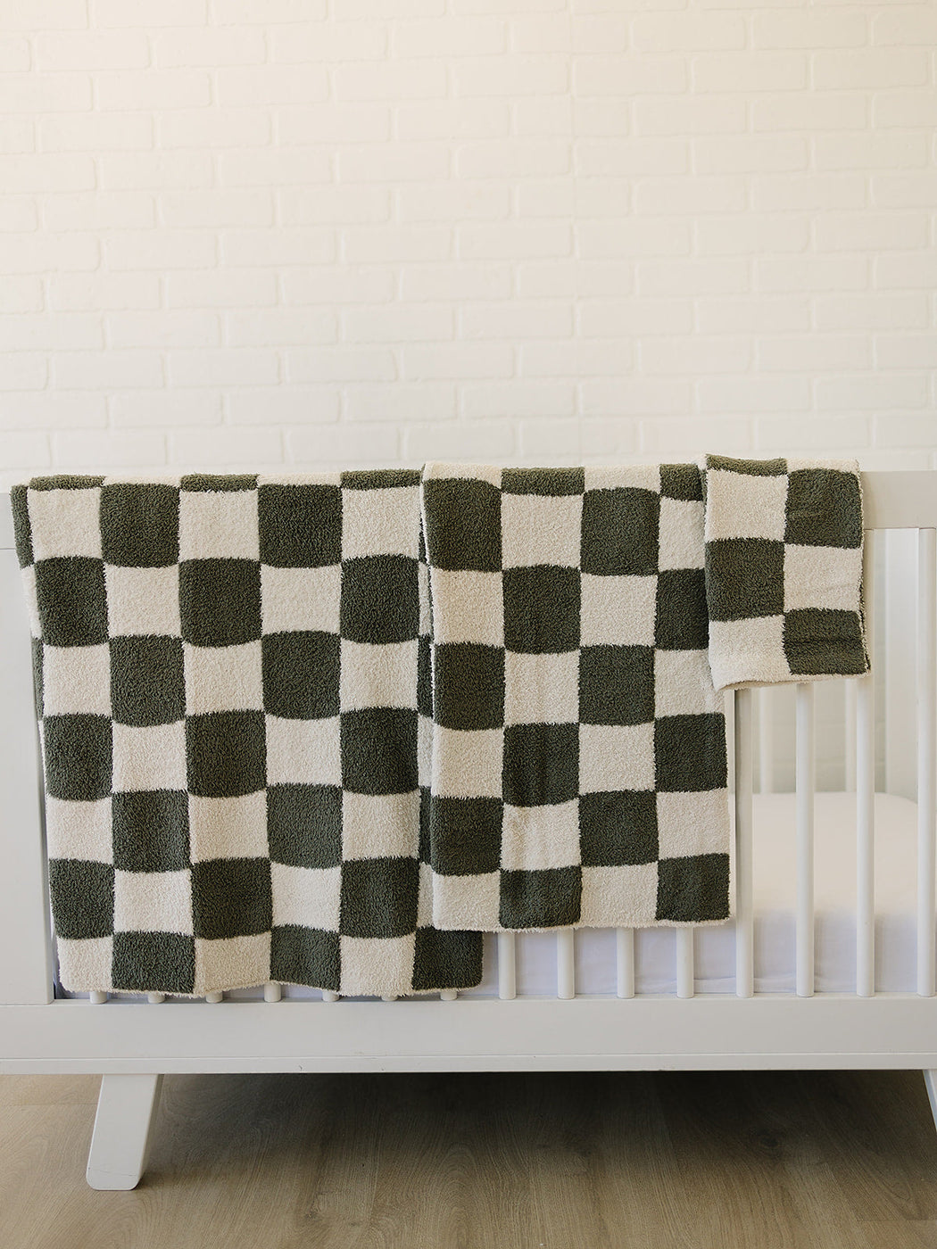 a white crib with a black and white checkered blanket