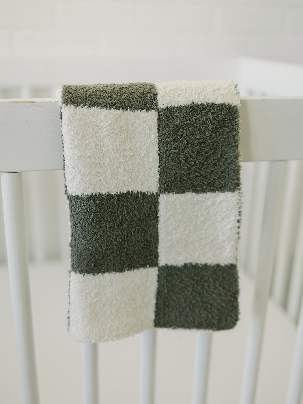 a green and white checkered towel on a white crib