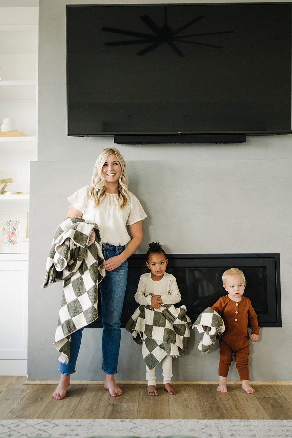 a woman and kids standing in front of a fireplace