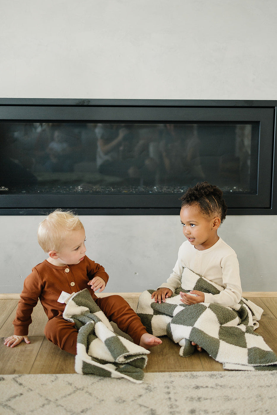 a couple of children sitting on the floor in front of a fireplace