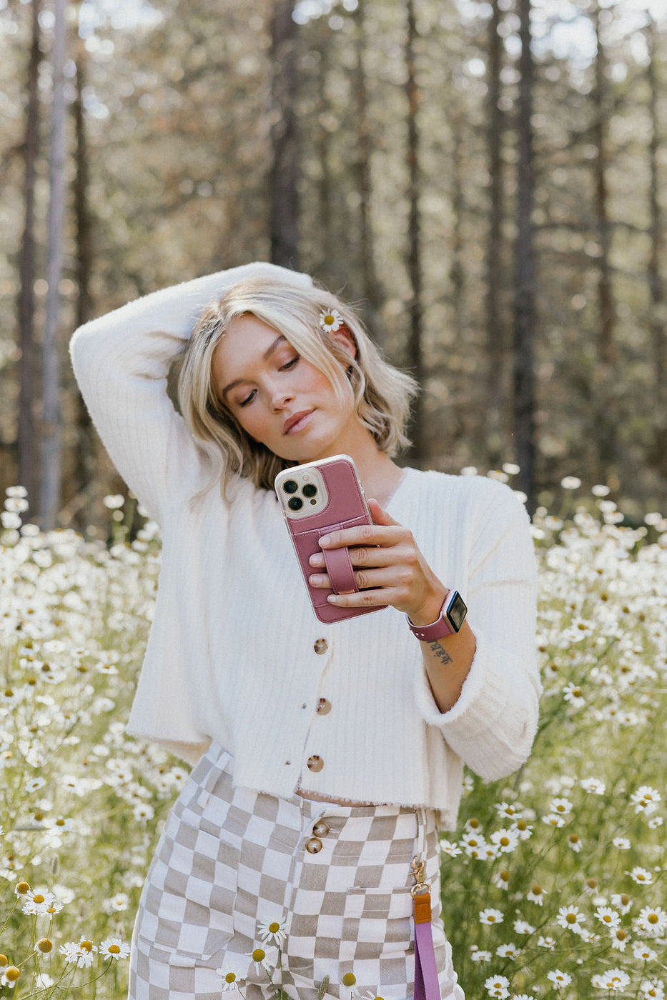 a woman holding a phone in a field of flowers