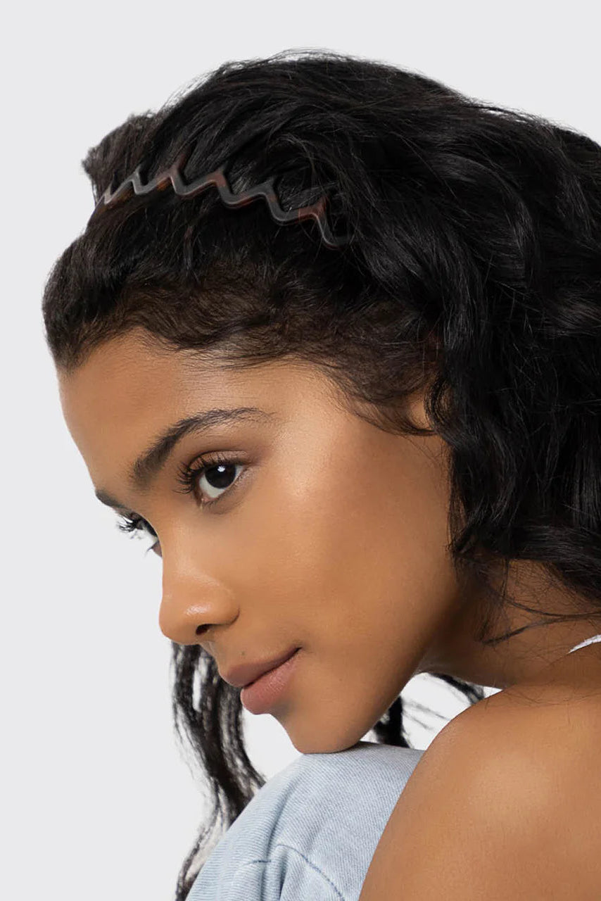 Woman with styled hair wearing a headband against a neutral background