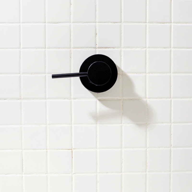 a black handle on a white tile wall